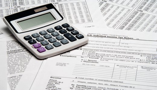 A calculator sitting on top of tax forms.